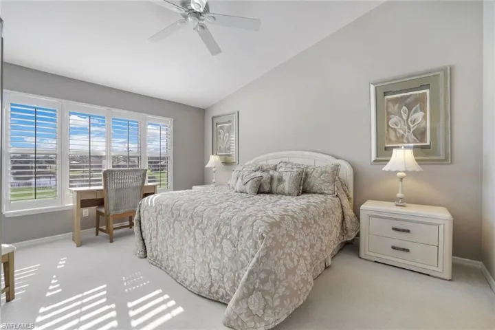 Bedroom with ceiling fan, light colored carpet, and vaulted ceiling