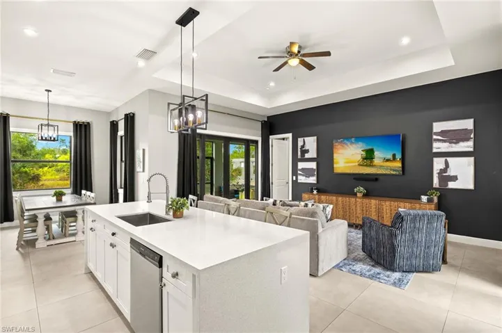 Kitchen featuring light tile patterned floors, white cabinetry, a tray ceiling, dishwasher, and a sink