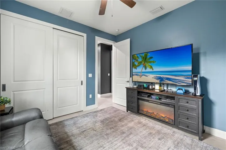 Living room with visible vents, ceiling fan, a glass covered fireplace, and baseboards
