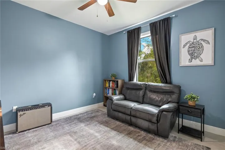 Living area featuring baseboards and ceiling fan