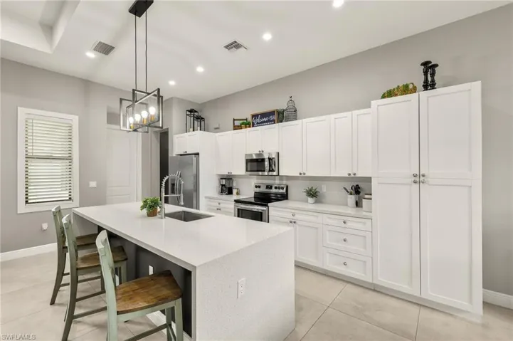 Kitchen with visible vents, a sink, a center island with sink, and appliances with stainless steel finishes