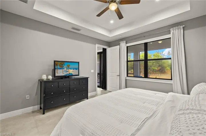 Bedroom featuring recessed lighting, a tray ceiling, baseboards, and a ceiling fan