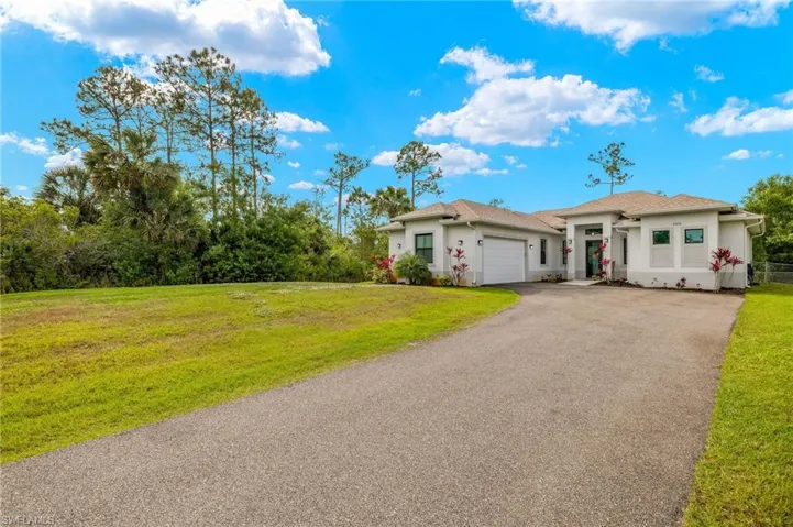 View of front of house featuring a front yard, driveway, stucco siding, and an attached garage