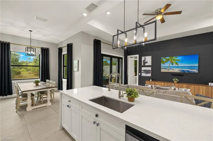 Kitchen with open floor plan, light countertops, white cabinetry, visible vents, and a sink