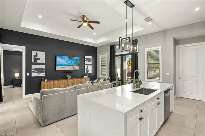 Kitchen featuring white cabinets, visible vents, a raised ceiling, stainless steel dishwasher, and a sink