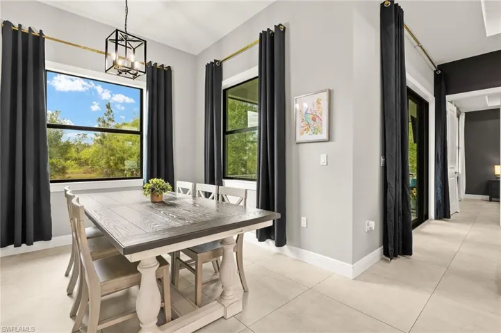 Dining room with a chandelier, light tile patterned floors, and baseboards