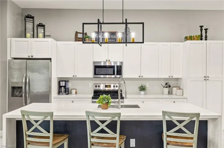 Kitchen with tasteful backsplash, light countertops, white cabinets, and stainless steel appliances