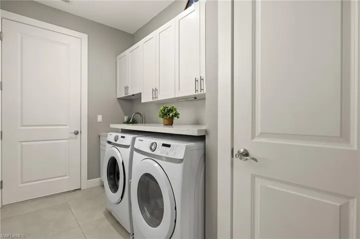 Laundry area featuring cabinet space, separate washer and dryer, and light tile patterned flooring