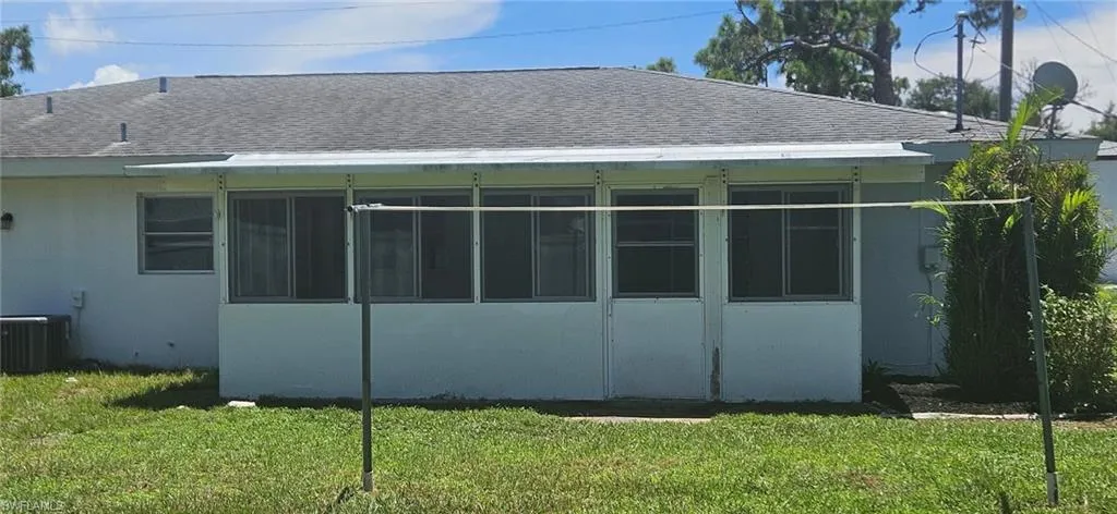 View of side of property with a yard, a sunroom, and central AC unit