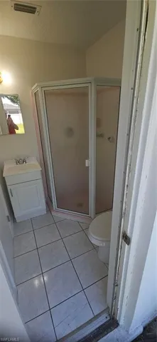 Bathroom with vanity, walk in shower, toilet, and tile patterned floors