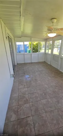 Unfurnished sunroom featuring plenty of natural light, beam ceiling, and ceiling fan