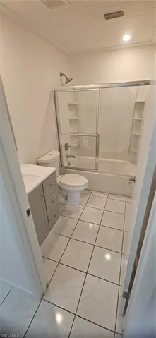 Full bathroom with vanity, tile patterned floors, toilet, and enclosed tub / shower combo