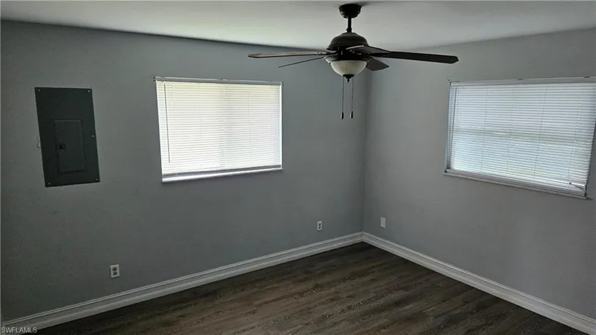 Unfurnished room featuring dark wood finished floors, electric panel, and ceiling fan