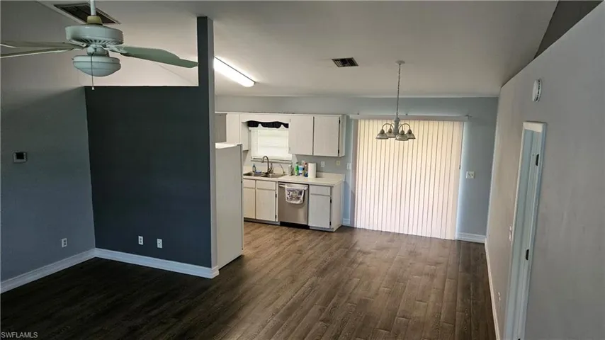Kitchen featuring light countertops, dark wood-style flooring, dishwasher, ceiling fan, and freestanding refrigerator