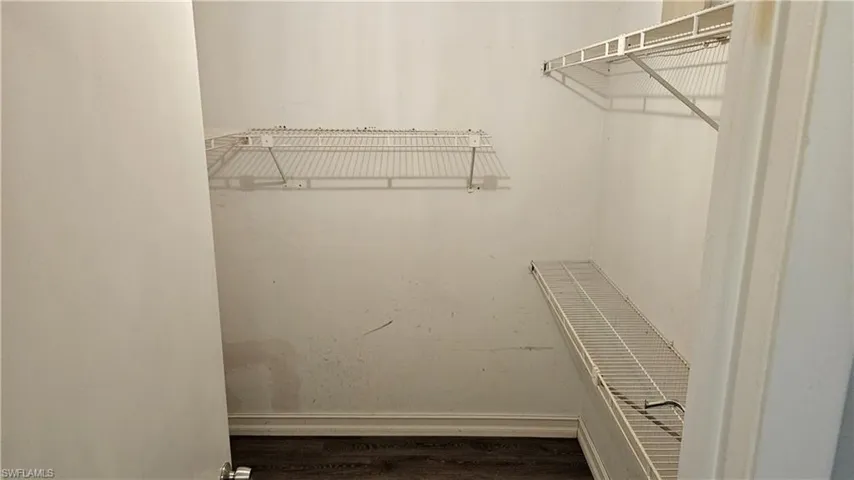 Walk in closet with dark wood finished floors