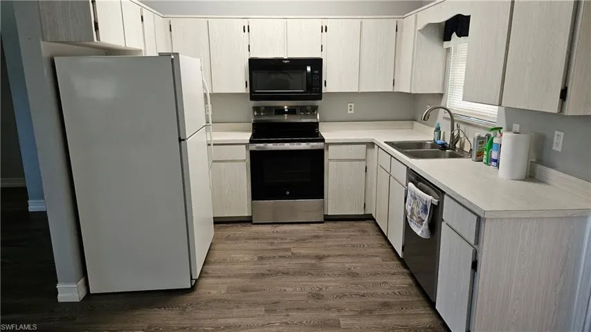 Kitchen featuring light countertops, appliances with stainless steel finishes, and dark wood-type flooring