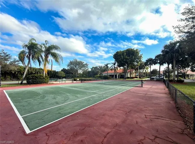 Tennis court with a green playing surface and perimeter fencing