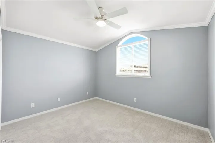 Room featuring an arched window, white blinds, and a neutral carpet