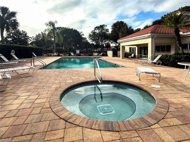 Outdoor spa and swimming pool with paver decking, surrounded by tropical landscaping