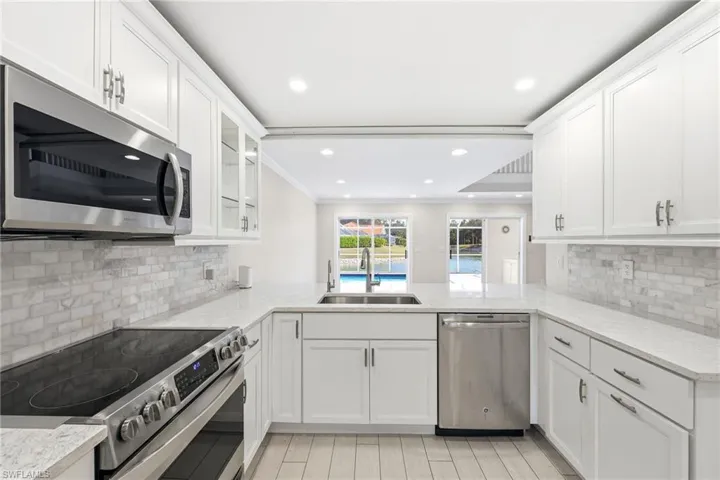 Bright kitchen featuring white cabinetry and stainless steel appliances