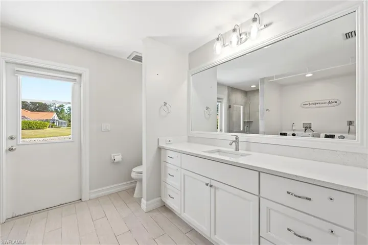 Bathroom featuring a single vanity with stone countertop, undermount sink, and brushed nickel faucet