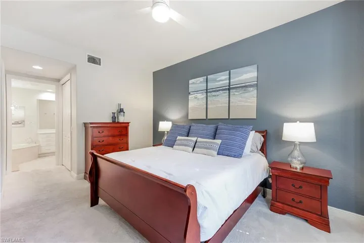 Carpeted bedroom with ensuite bath and ceiling fan