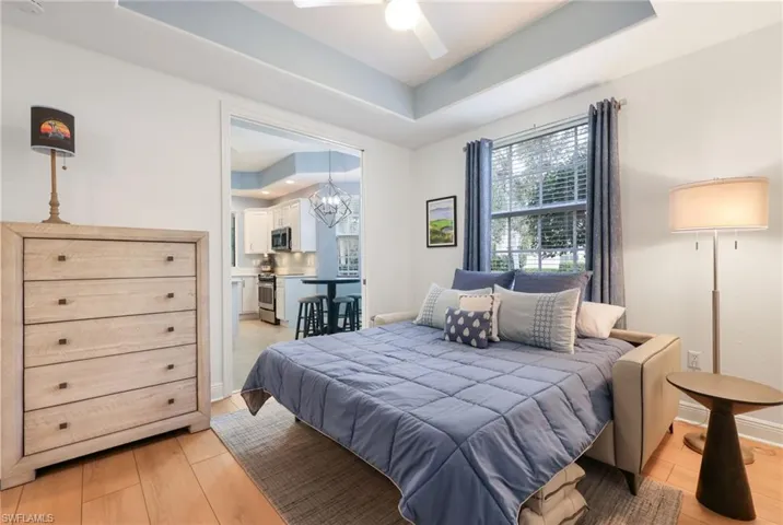 Den/Bedroom featuring a raised ceiling, ceiling fan with notable light hardwood / wood-style flooring