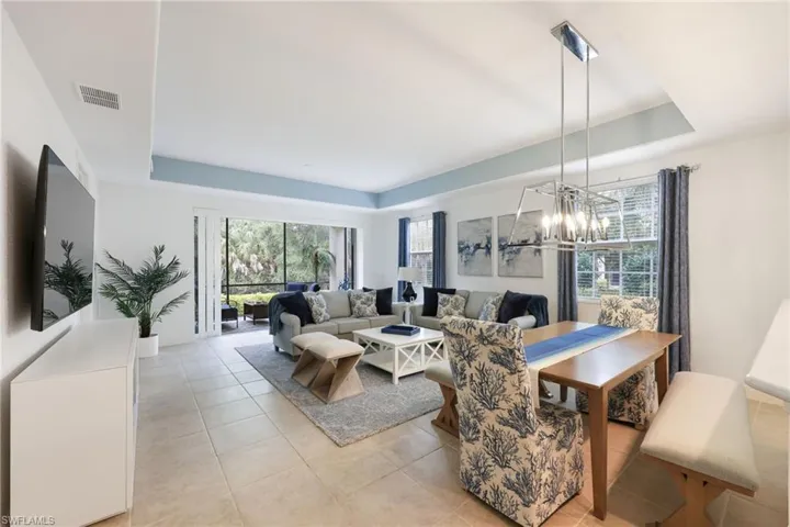 Turnkey furnished. Living room with a wealth of natural light, light tile patterned floors, and a raised ceiling