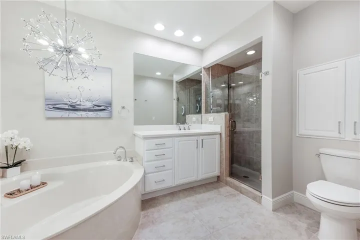 Full bathroom featuring an inviting chandelier, tile patterned flooring, separate shower and tub, toilet, and vanity
