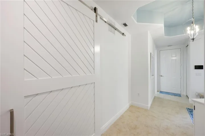 Hallway with an inviting chandelier and a barn door