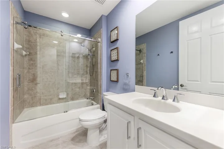 Full bathroom featuring tile patterned flooring, vanity, combined bath / shower with glass door, and toilet