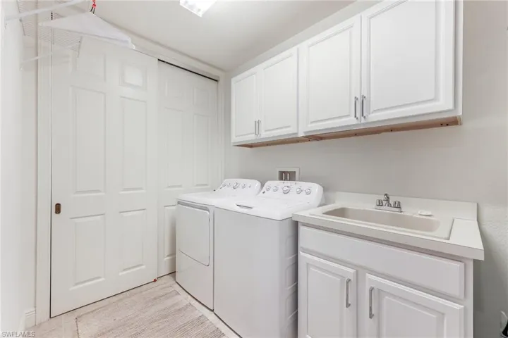 Washroom with washer and dryer, cabinets, and sink