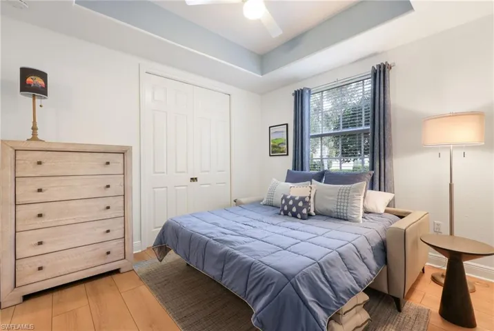 Bedroom featuring light wood-type flooring, ceiling fan, a closet, and a raised ceiling