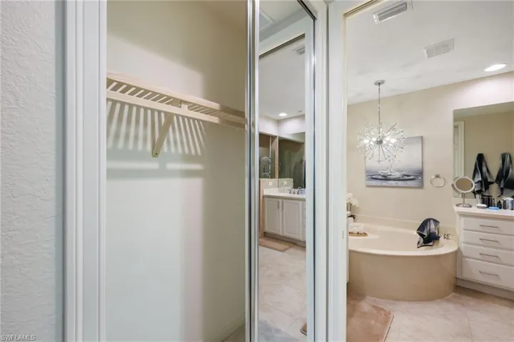 Bathroom with tile patterned flooring, a chandelier, a washtub, and vanity