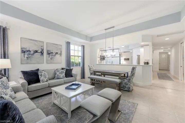 Living room featuring a raised ceiling, an inviting chandelier, and light tile patterned flooring