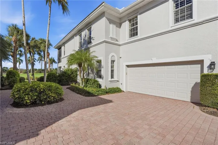 View of front facade with an attached garage, driveway, and stucco siding