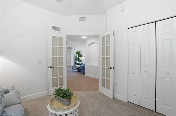 Sitting room with light carpet, arched walkways, and french doors
