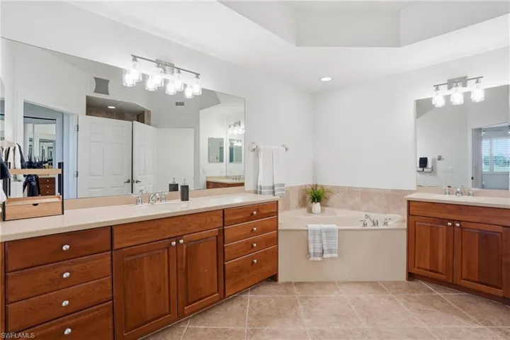 Bathroom featuring two vanities and a garden tub
