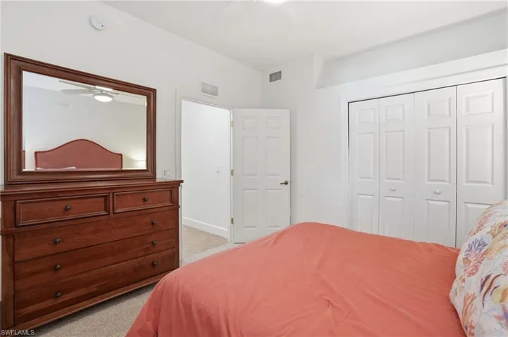 Bedroom featuring light colored carpet, a closet, and a ceiling fan