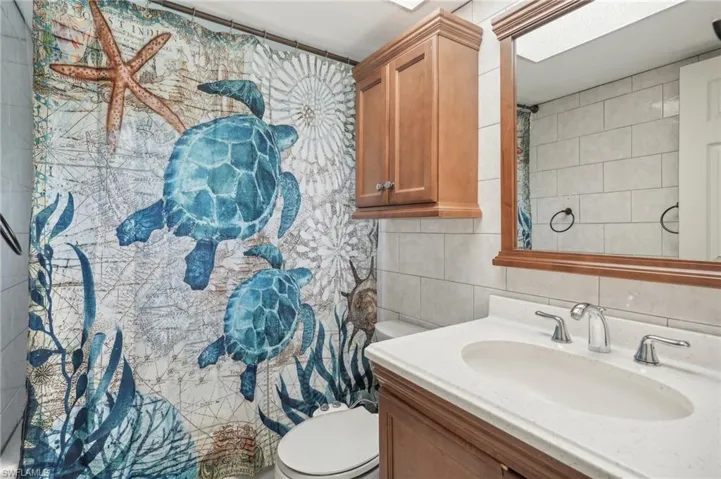 Bathroom featuring tile walls, tasteful backsplash, large vanity, and toilet