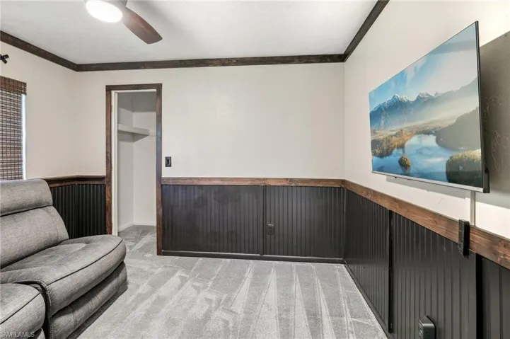 Living area featuring ceiling fan, crown molding, and light carpet