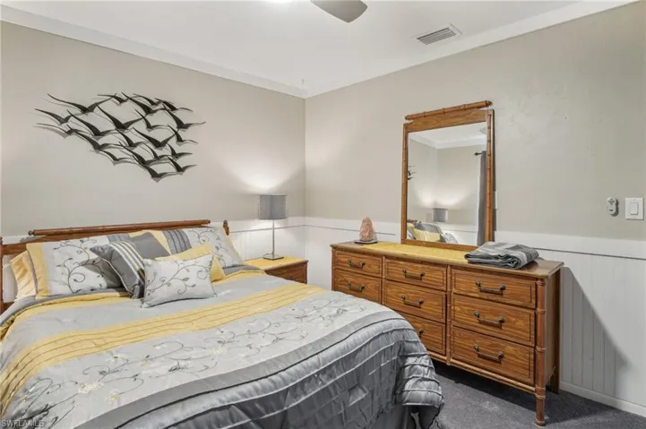 Bedroom with ornamental molding, dark colored carpet, and ceiling fan