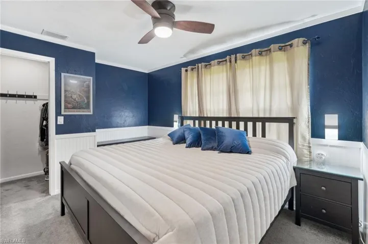 Carpeted bedroom with ceiling fan and a closet