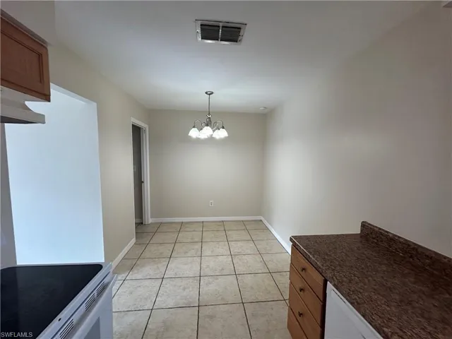 Unfurnished dining area featuring hanging lights and light tile patterned floors