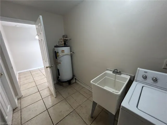 Laundry area featuring washer / dryer, electric water heater, and light tile patterned flooring
