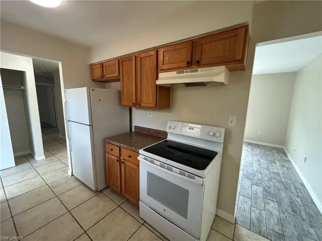 Kitchen featuring wood finish cabinetry, white appliances, and dark countertops
