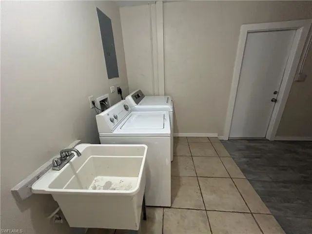 Laundry area featuring light tile patterned flooring, electric panel, and washing machine and dryer