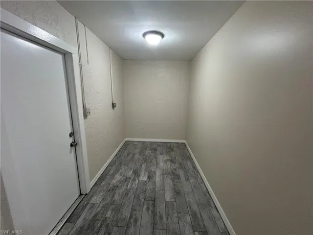 Hall featuring dark wood-style floors and a textured wall