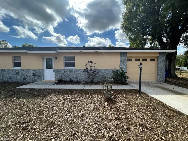 Ranch-style house with stone siding, stucco siding, concrete driveway, and an attached garage