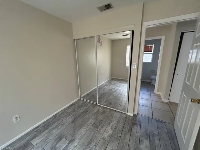 Unfurnished bedroom featuring dark wood-style flooring and a closet